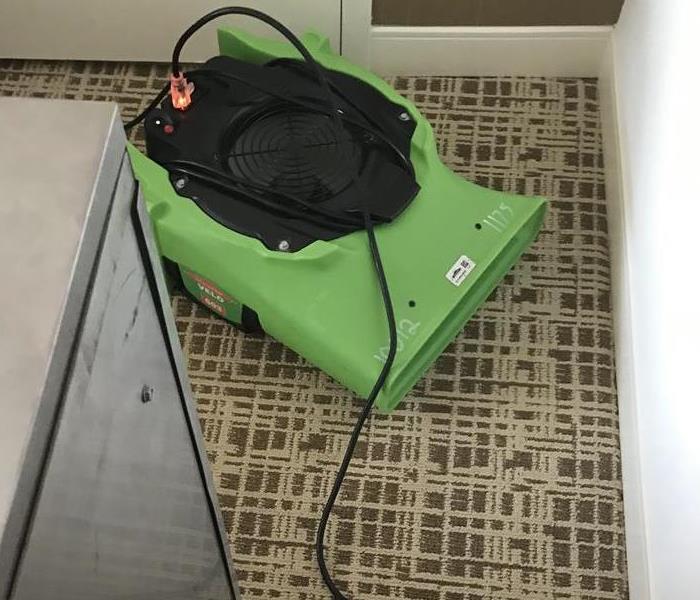 One green air mover on the floor. 