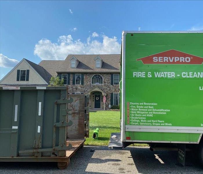 SERVPRO truck and dumpster outside of a brick home. 